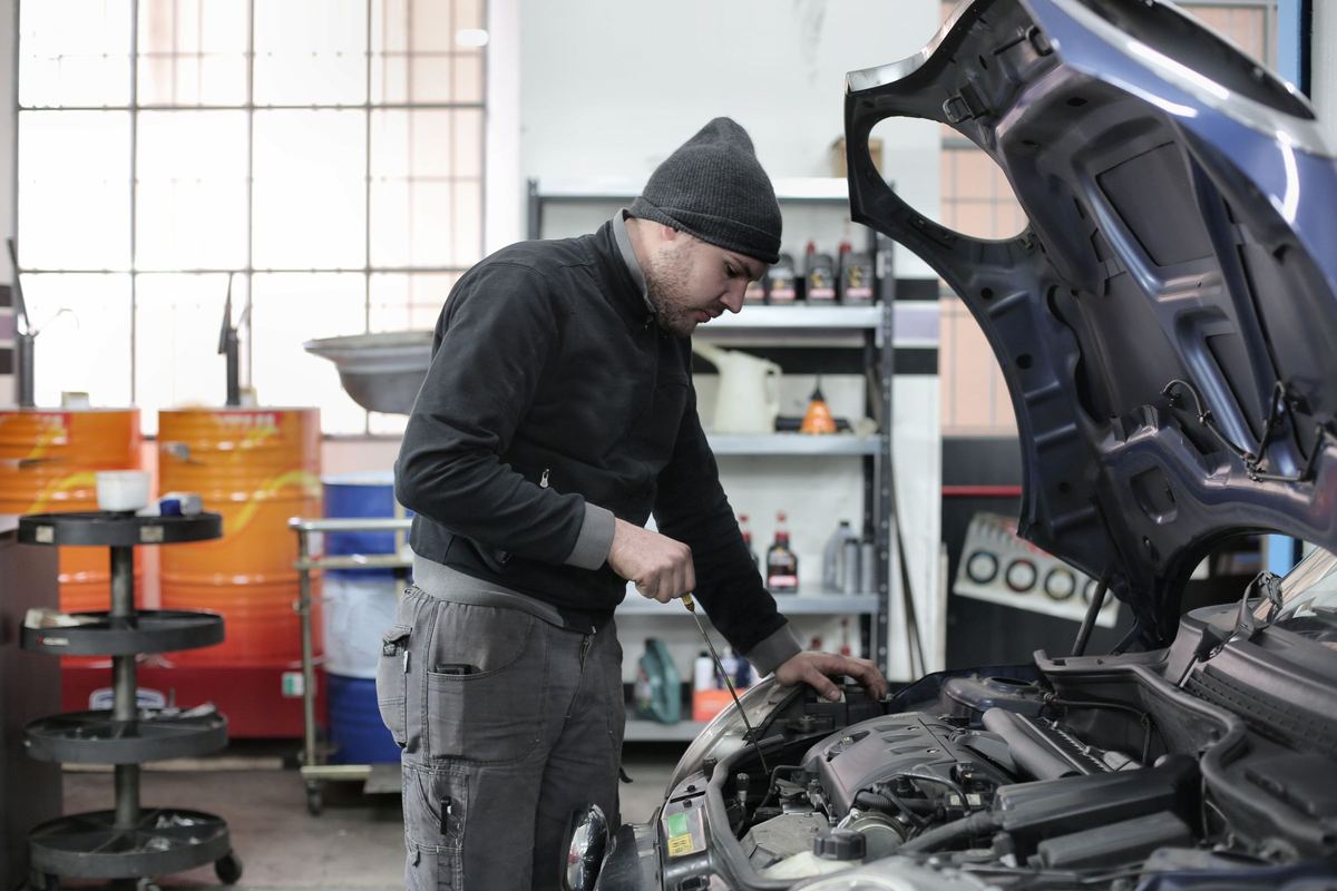 Een mechanieker controleert het oliepeil onder de open motorkap